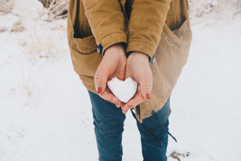 Žena drží v rukách sneh v tvare srdca