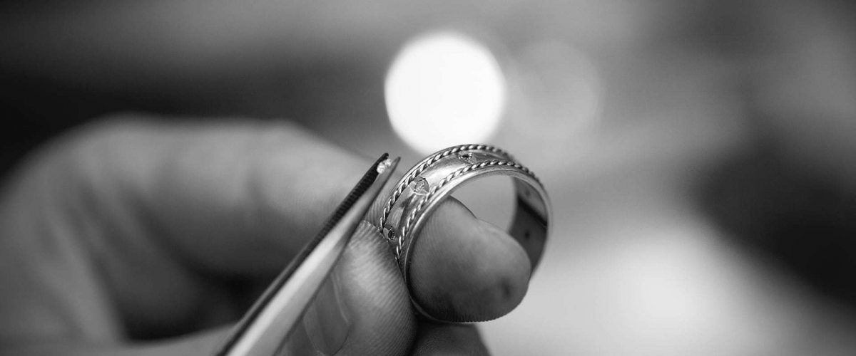 Klenotník osádzajúci diamant na svadobnú obrúčku - čiernobiela fotografia