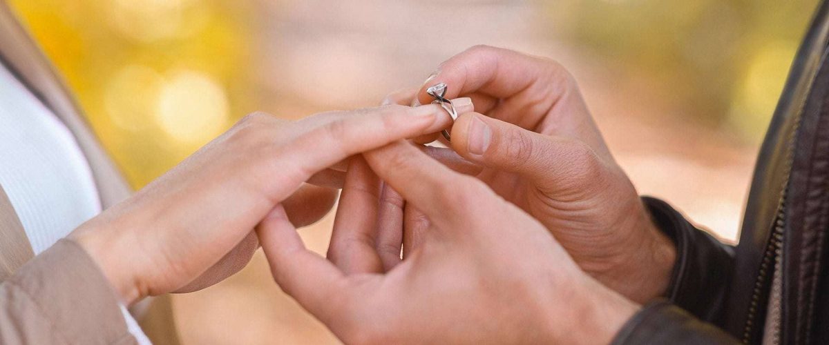 muž navlieka zásnubný prsteň na prstenník ľavej ruky svojej vyvolenej